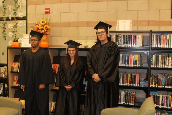 Graduates posing in the Triumph library before a brief ceremony